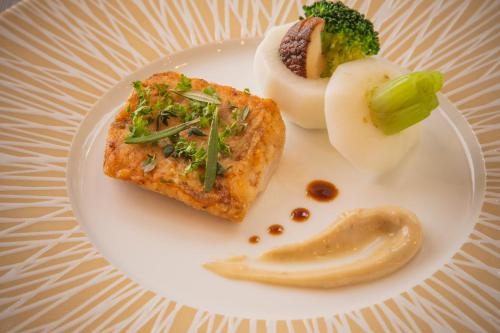 a plate of food with broccoli and a piece of fish at La Vista Furano Hills Natural Hot Spring in Furano