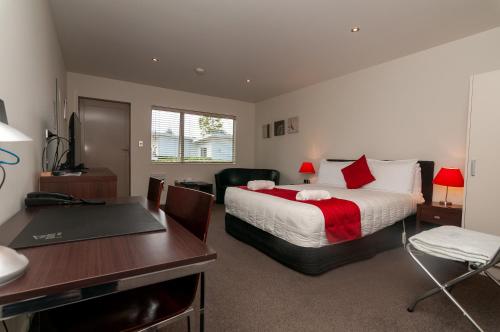 a hotel room with a bed and a desk and a desk at The Park Motel in Hawera