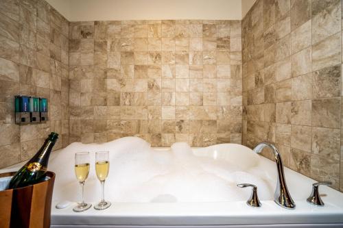 Lucky Eagle Casino & Hotel (Washington) في Rochester: حوض استحمام مع كأسين من النبيذ وزجاجة من الشمبانيا