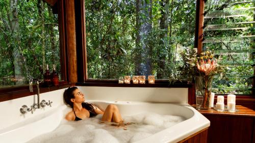 a woman is sitting in a bath tub at The Canopy Rainforest Treehouses & Wildlife Sanctuary in Tarzali