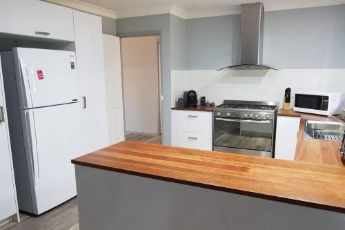 uma cozinha com electrodomésticos brancos e uma bancada de madeira em Blue Wren BnB Bathurst em Bathurst