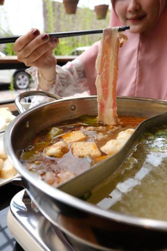 a woman is stirring a pot of soup at Baratha Hotel & Resto in Bondowoso