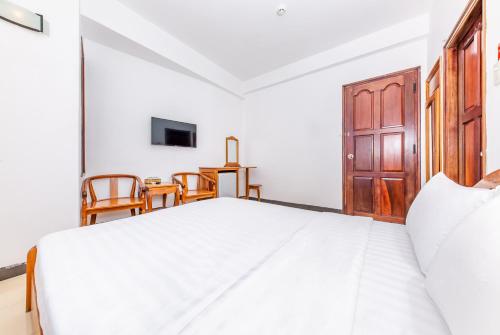 1 dormitorio con cama blanca y puerta de madera en Minh Cat Hotel, en Nha Trang