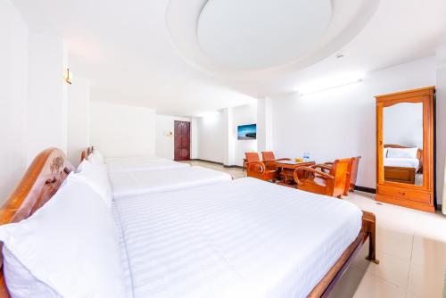 a bedroom with a large white bed and a desk at Minh Cat Hotel in Nha Trang