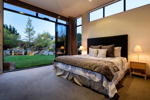 a bedroom with a large bed and large windows at Dunalistair House at The Kinloch Club Golf Course in Kinloch