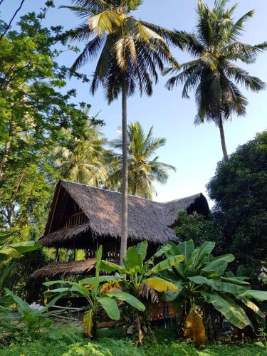 a bamboo house with palm trees in the background at Antonio's Ko Yao Noi in Ko Yao Noi