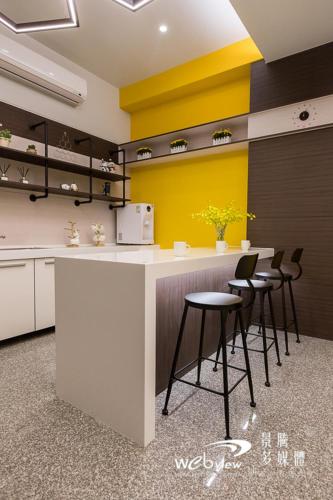 a kitchen with a counter with stools and yellow walls at FDBK Homestay in Dongshan