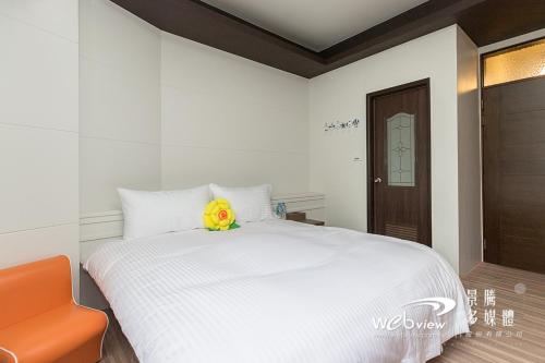 ein Schlafzimmer mit einem weißen Bett mit einer gelben Blume darauf in der Unterkunft FDBK Homestay in Dongshan