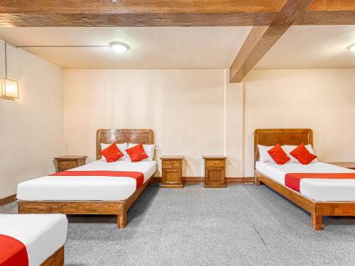 two beds in a room with red pillows at Hotel Esperanza, Oaxaca Centro in Oaxaca City
