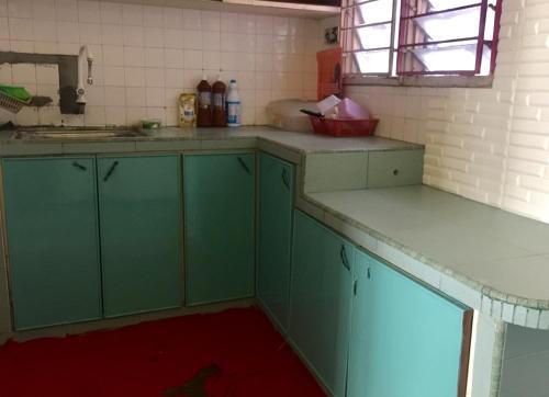 an empty kitchen with green cabinets and a sink at Pesona Backpackers Inn in Kota Bharu