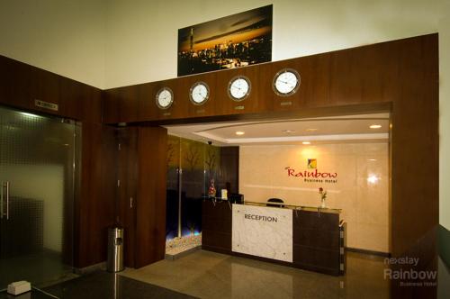 a hotel lobby with clocks on the wall and a reception desk at New Rainbow Business Hotel in Bangalore