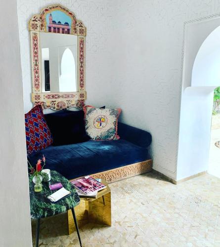 ein Wohnzimmer mit einem blauen Sofa und einem Spiegel in der Unterkunft P´tit Habibi in Marrakesch
