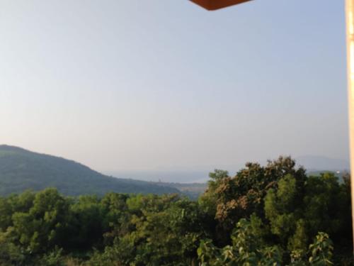 a view of trees and mountains in the distance at Redstone Hills, Diveagar in Diveagar
