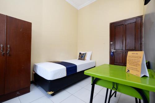 a small bedroom with a bed and a green table at Hotel O Solo Point Guest House Syariah in Solo