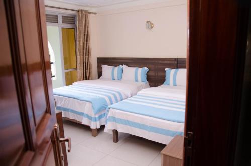 a bedroom with two beds with blue and white sheets at Agenda 2000 Hotels Ltd in Kampala