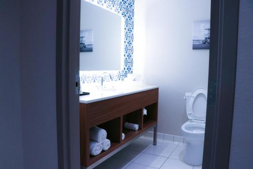 a bathroom with a sink, toilet and mirror at Days Inn & Suites by Wyndham Fort Myers Near JetBlue Park in Fort Myers