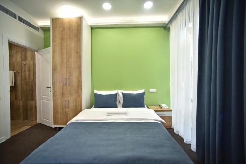 a bedroom with a large bed and a green wall at Bonjour Boutique Hotel Yerevan in Yerevan