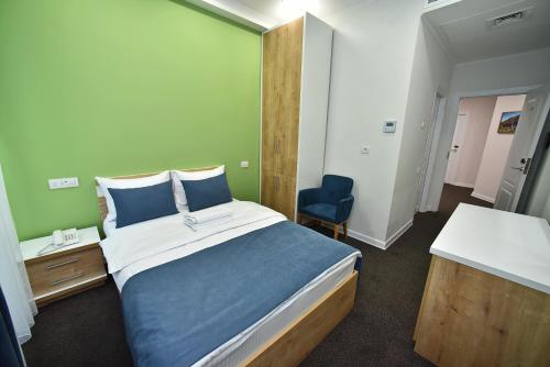 a bedroom with a large bed and a blue chair at Bonjour Boutique Hotel Yerevan in Yerevan