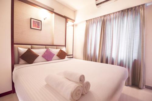 a bedroom with a white bed with towels on it at D Homz Suites in Cochin