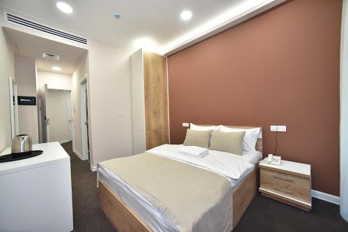 a bedroom with a large bed and a brown wall at Bonjour Boutique Hotel Yerevan in Yerevan