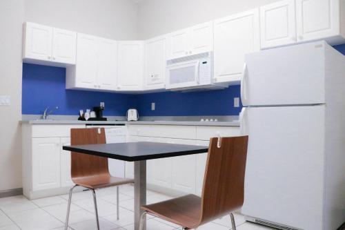 a kitchen with a table and chairs and a refrigerator at Days Inn & Suites by Wyndham Fort Myers Near JetBlue Park in Fort Myers