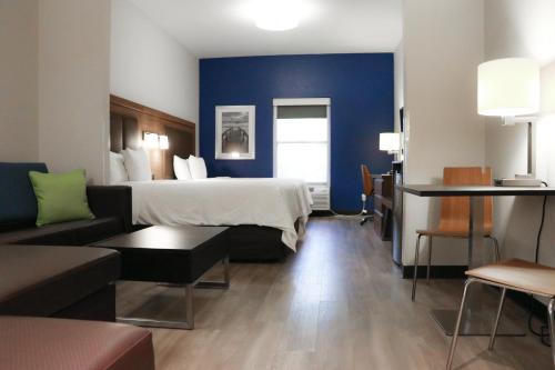 une chambre d'hôtel avec un lit et un canapé dans l'établissement Days Inn & Suites by Wyndham Fort Myers Near JetBlue Park, à Fort Myers
