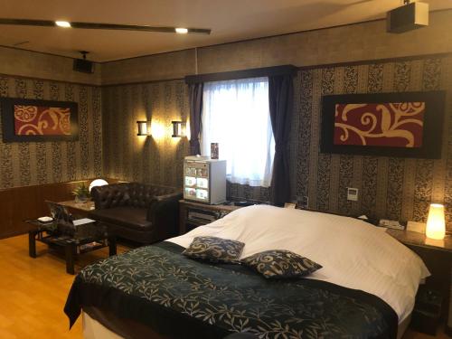 um quarto com uma cama, uma cadeira e uma janela em Restay Penthouse (Adult Only) em Kitakyushu