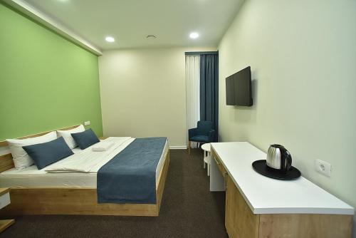 a bedroom with a bed and a desk and a television at Bonjour Boutique Hotel Yerevan in Yerevan