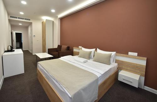 a bedroom with a large bed and a chair at Bonjour Boutique Hotel Yerevan in Yerevan