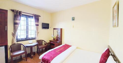 a bedroom with a bed and a table and a window at Thanh Thao Dalat Hotel in Da Lat