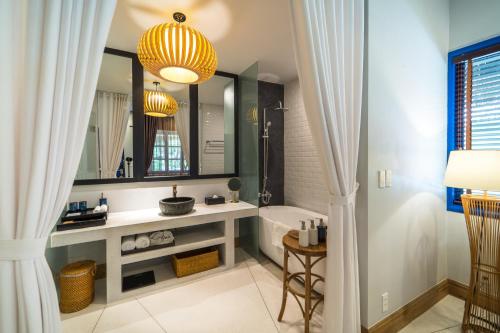 a bathroom with a tub and a sink and a mirror at L'Azure Resort and Spa in Phú Quốc