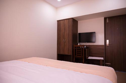 a bedroom with a bed and a flat screen tv at Hotel Sharda Residency in Mangalore