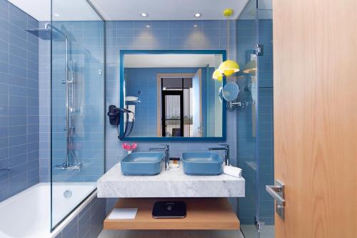 a blue bathroom with a sink and a mirror at C Central Hotel and Resort The Palm in Dubai