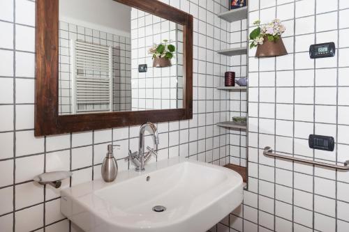 a white tiled bathroom with a sink and a mirror at Agriturismo Terre Bianche in Teolo