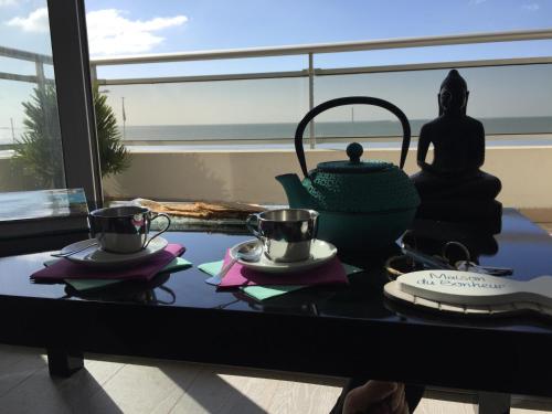 - une table avec deux tasses et une théière dans l'établissement Face Mer 