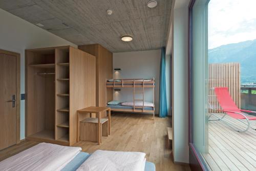 a bedroom with a bed and a desk and a balcony at Interlaken Youth Hostel in Interlaken