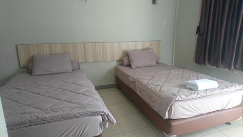 two beds sitting next to each other in a room at Liberty Homestay in Parit