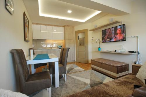 a living room with a table and a kitchen at Apartman Vip Aleksa Zlatibor Centar in Zlatibor
