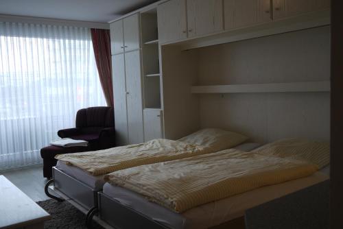1 Schlafzimmer mit 2 Betten, einem Stuhl und einem Fenster in der Unterkunft Korn in Westerland