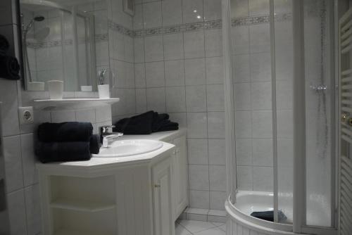 ein weißes Bad mit einem Waschbecken und einer Dusche in der Unterkunft Korn in Westerland