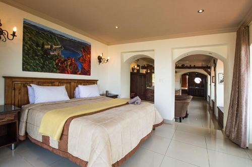 a bedroom with a large bed with a painting on the wall at Stephan's Guest House in Port Shepstone