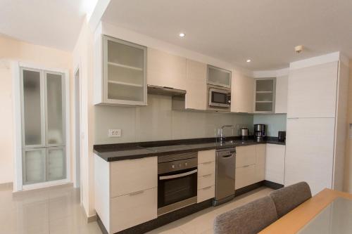 a kitchen with white cabinets and white appliances at Pearly Grey Ocean Club Apartments & Suites in Callao Salvaje