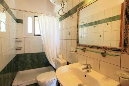 a bathroom with a sink and a toilet and a mirror at Cochelli Villas in Kassiopi