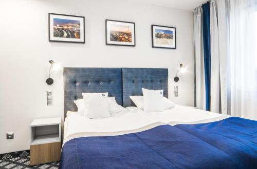 a bedroom with a large bed with a blue blanket at Hotel Urbi in Gdańsk
