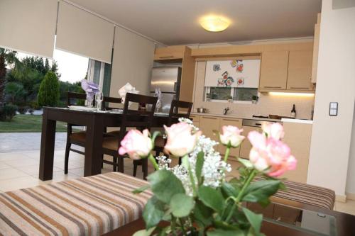 a kitchen and dining room with a table and flowers at Luxury heated pool Villa in Lagonissi
