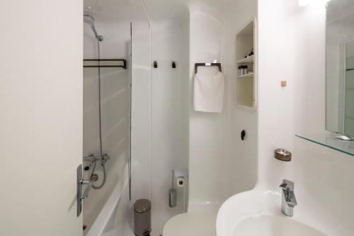 La salle de bains blanche est pourvue d'une douche et d'un lavabo. dans l'établissement La Cabine by Cocoonr, à Saint-Malo