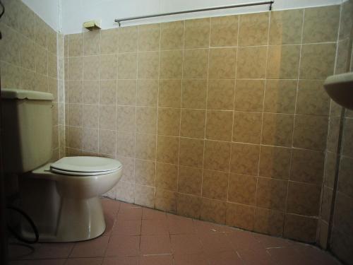 a bathroom with a toilet and a tiled wall at Redang Paradise Resort in Redang Island