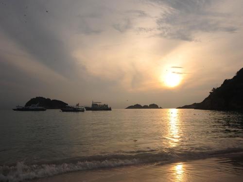 a sunset over a body of water with boats at Redang Paradise Resort in Redang Island