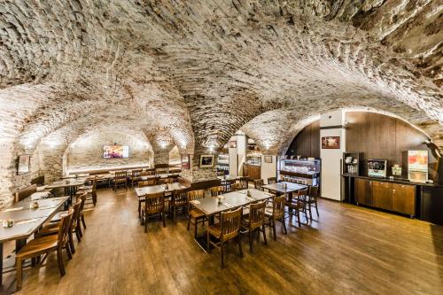 a restaurant with tables and chairs in a room with a stone wall at Archibald At the Charles Bridge in Prague