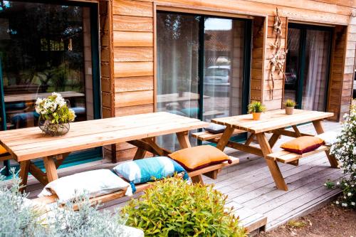 a wooden deck with a picnic table and benches at Gite La Marjeanerie in Ratières